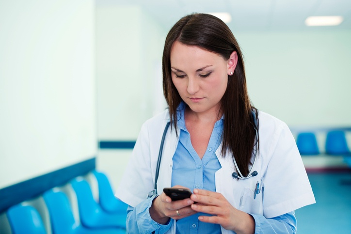 Doctor responding to urgent message on smartphone using HIPAA compliant cloud phone system softphone application