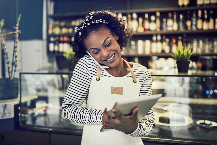 Happy barista chatting with a customer on the phone.