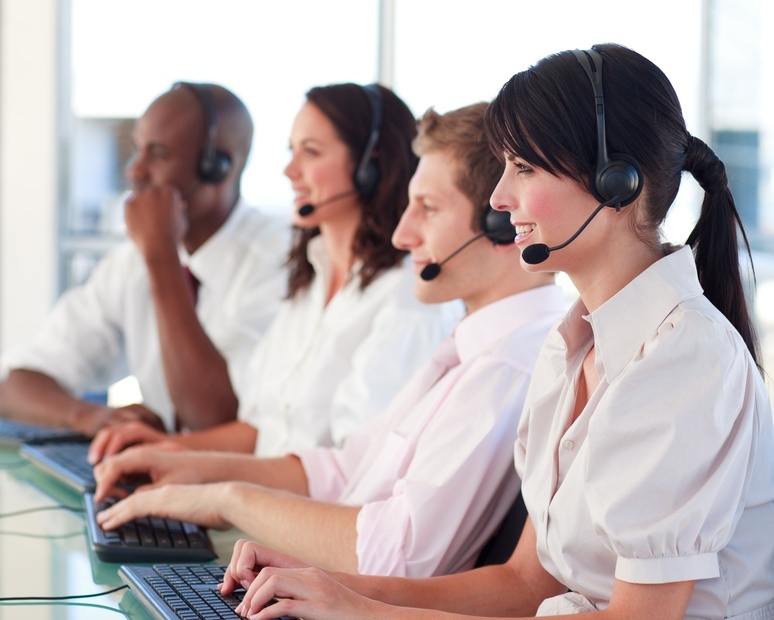 Group of happy contact center agents typing on computers.