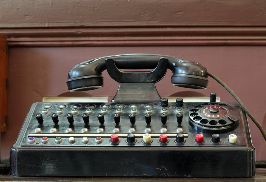 Outdated telephone with switches and rotary dial.