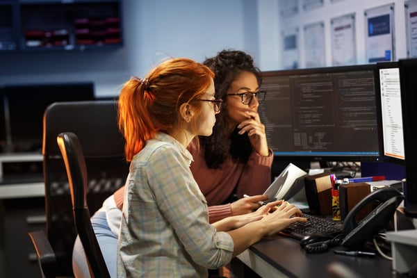 Two female colleagues looking at a computer screen using WebRTC.