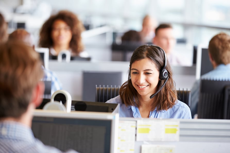 Woman in a call center speaking to a customer on a headset to keep her hands free.