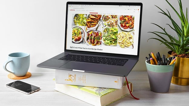 Image from Epicurious blog with a laptop on a stack of cookbooks.