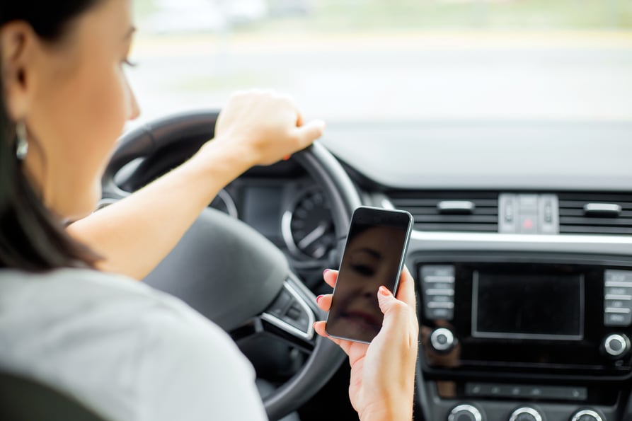 Businesswoman in a car holding up her smartphone.