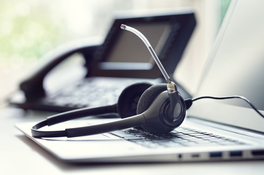 Picture of a phone headset on top of a laptop keyboard.