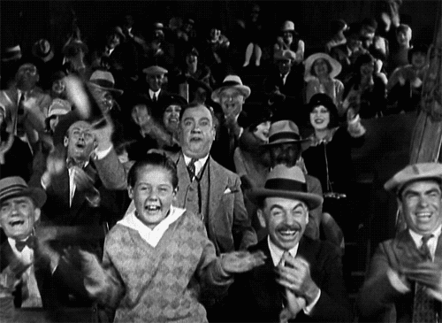 Black and white gif of old-timey audience cheering wildly.