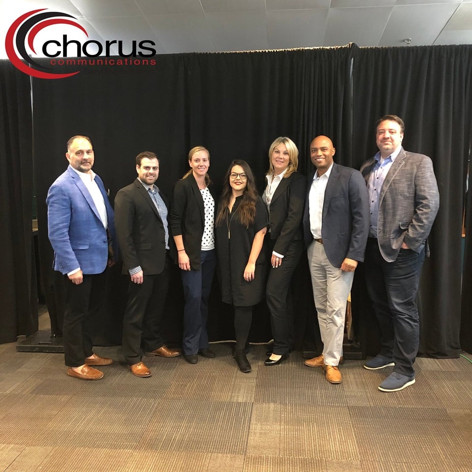 A group of Fall Forum panelists, including OnSIP's Helene Kidary, standing in front of a black curtain.