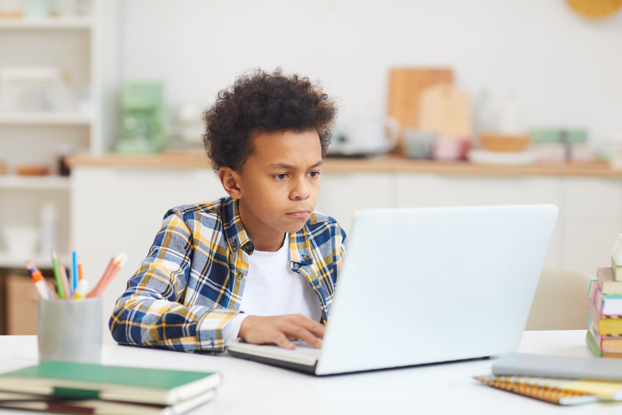 Young boy focusing on laptop screen at home.