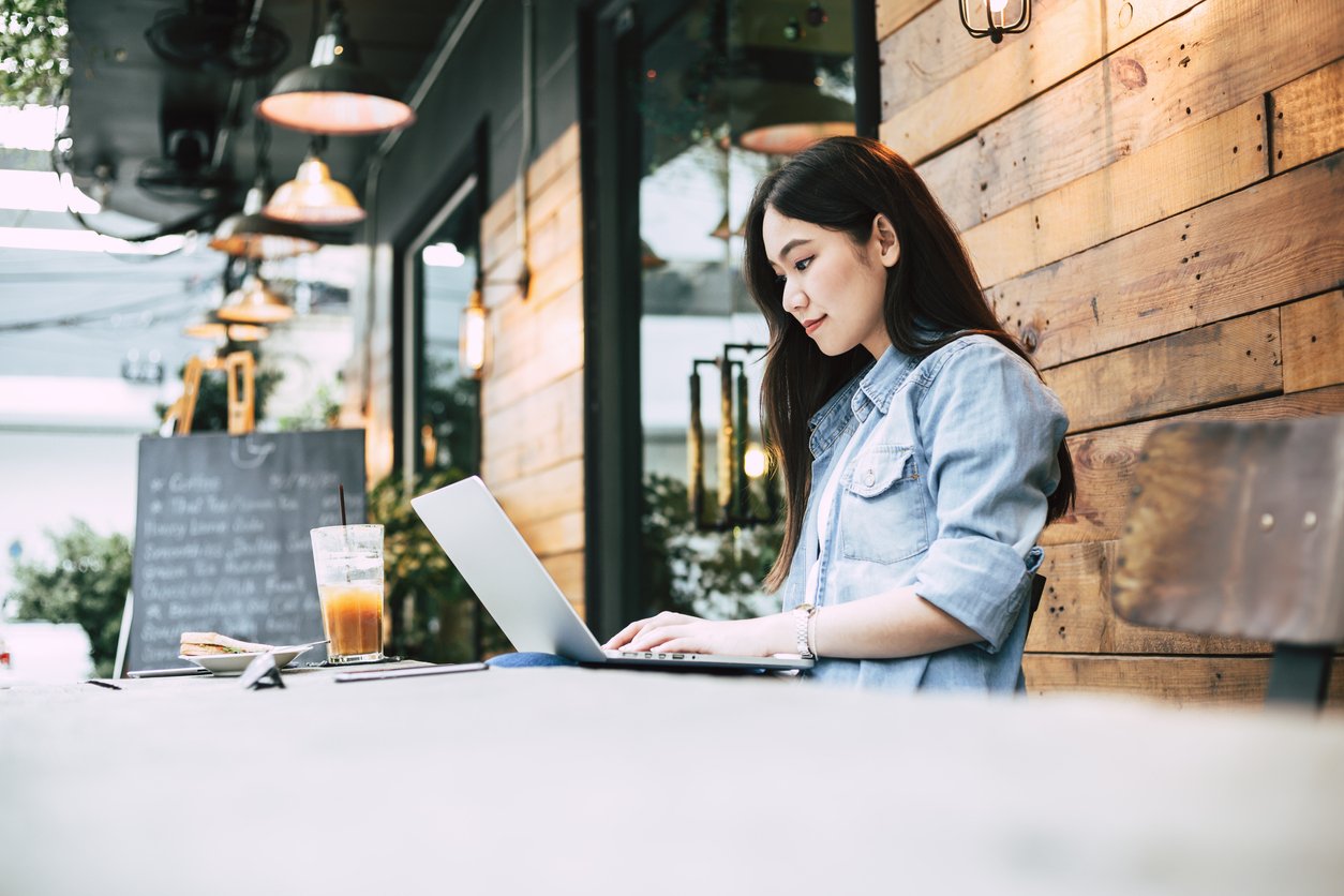 Woman on a laptop outside a coffee shop.