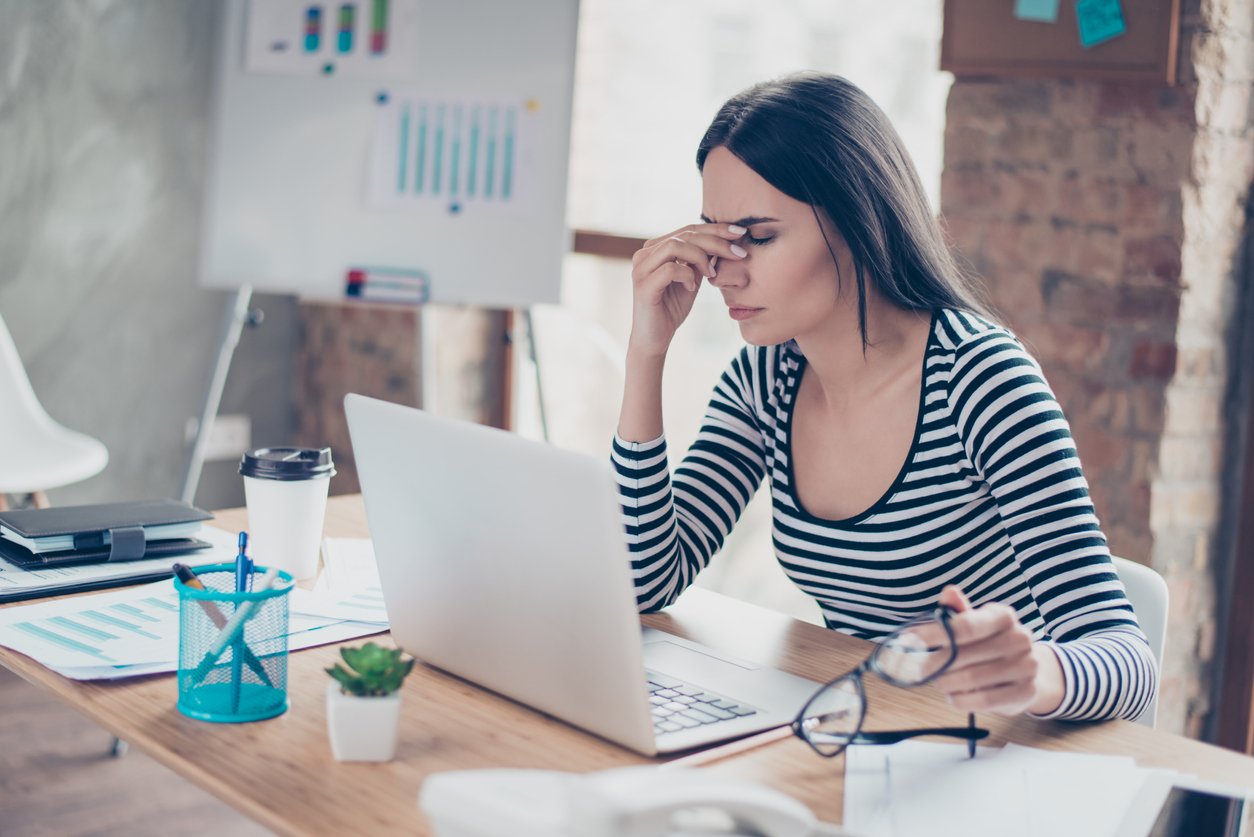 Frustrated-looking woman with a laptop waiting to speak to someone.