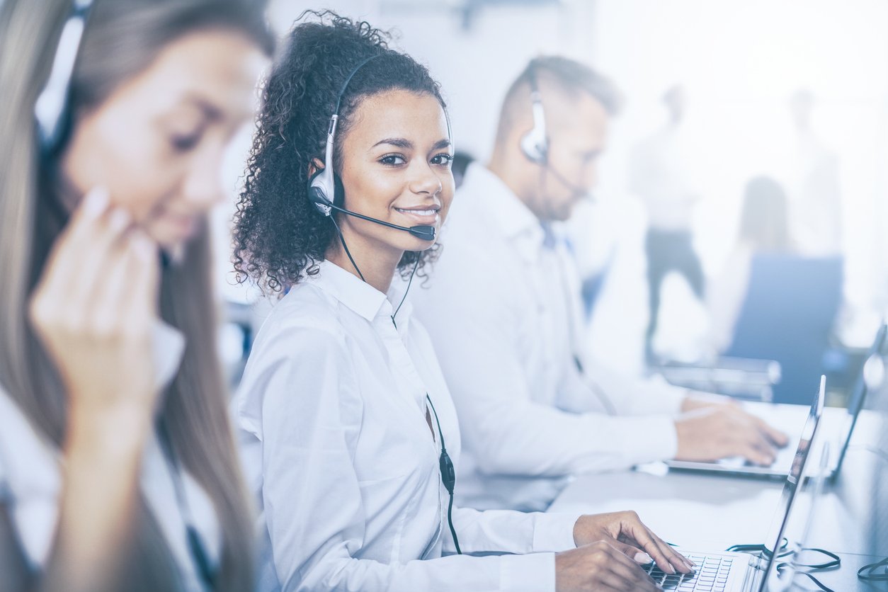 Woman wearing headset taking calls in a busy call center.