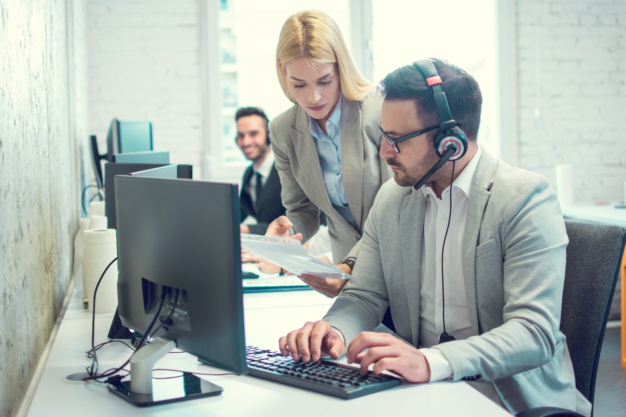 Business managers at a computer studying call activity report.