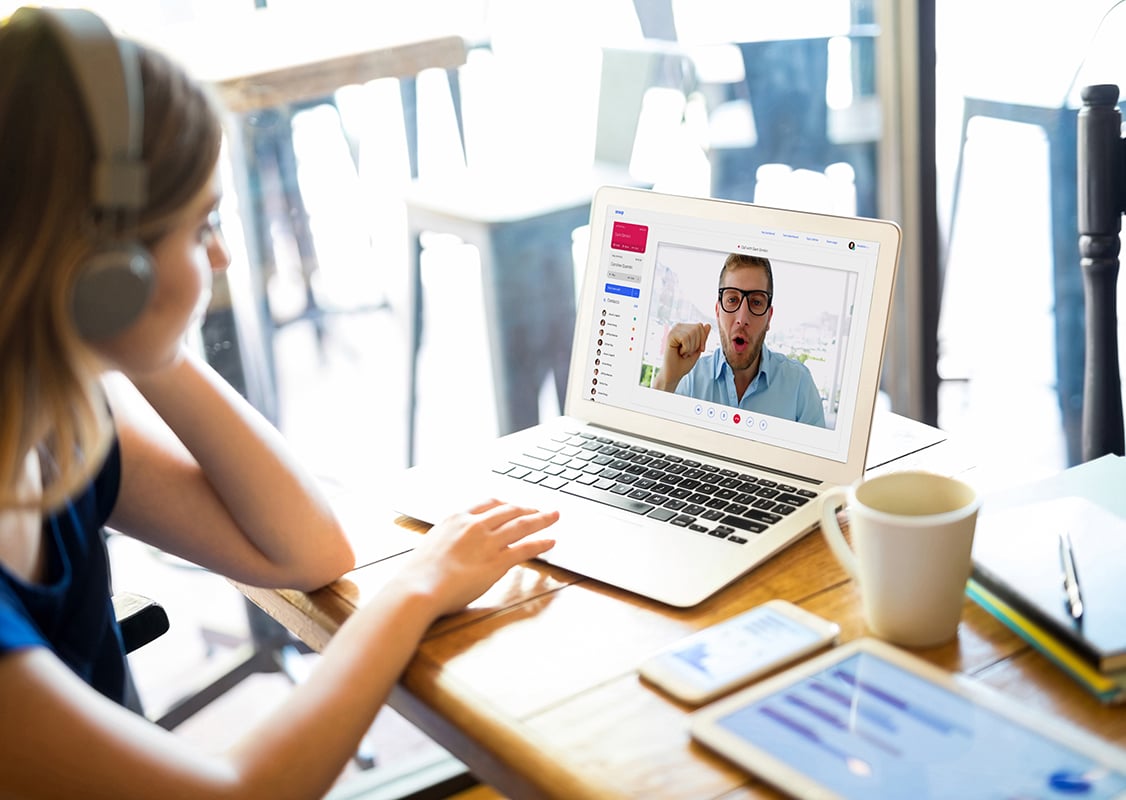 Woman with headphones taking a video call on her laptop.