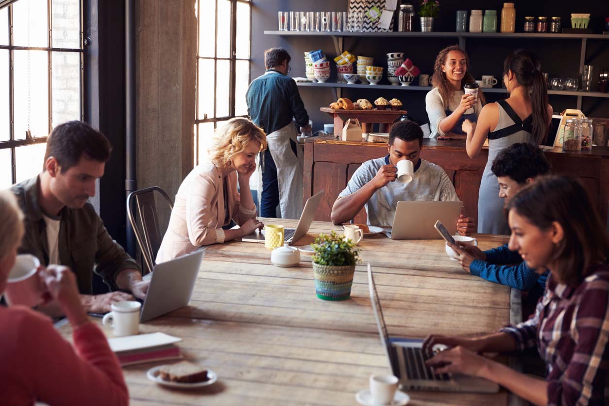 People working at a large table in a coffee shop.